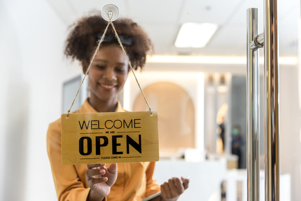 Happy employee turning an open sign in business establishment
